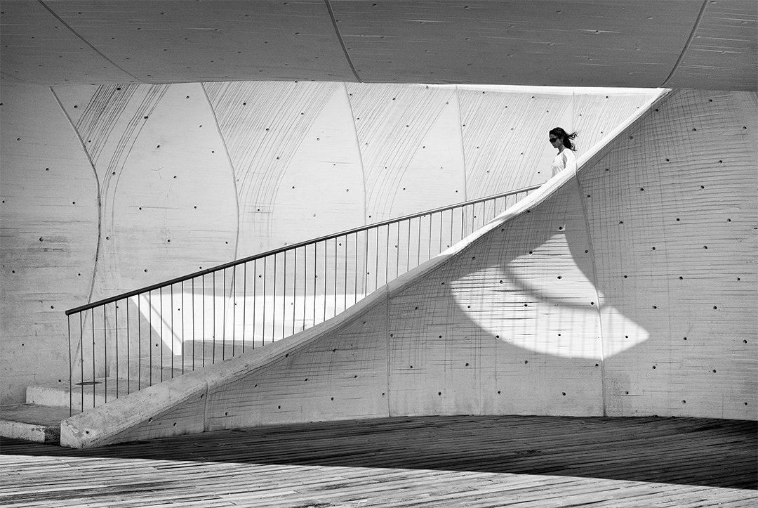 A figure on a curved ramp in front of a concrete wall.